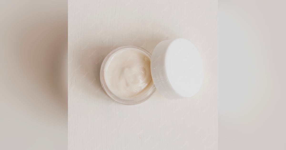 Pote de creme hidratante em close sobre fundo claro.